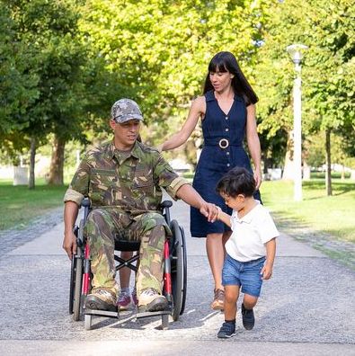 Disabled veteran in wheelchair with his wife and small child